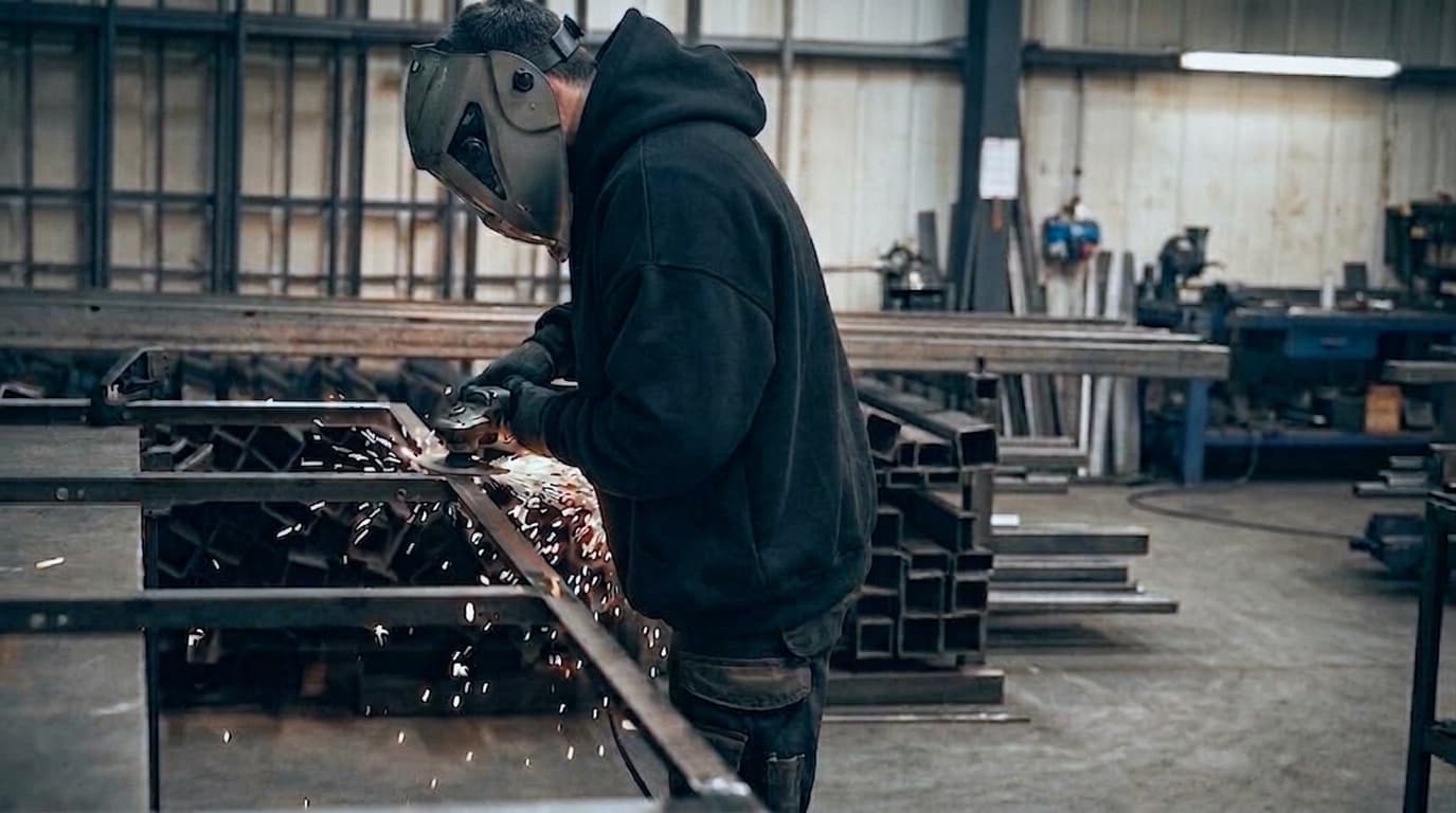Meulage d'un châssis acier à l'atelier, gerbe d'étincelles